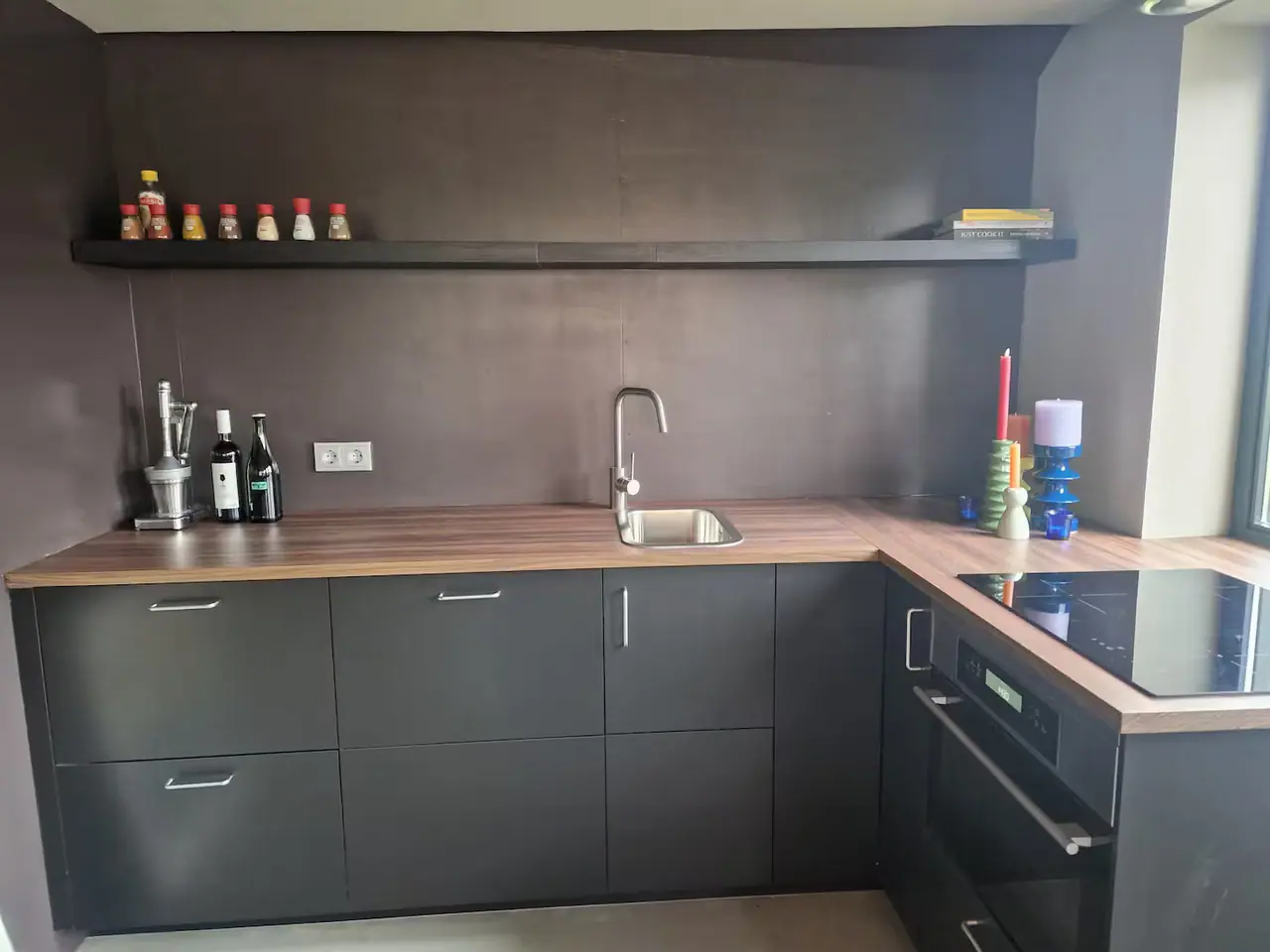 Nieuwe keuken met donkere kastjes, inductiekookplaat, oven en houten werkblad